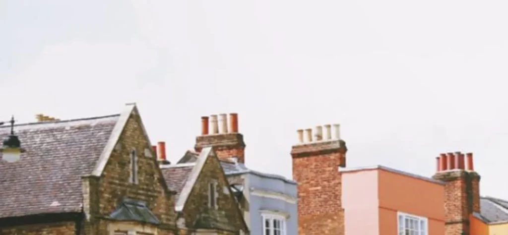 Row of traditional brick and stone houses with multiple chimney stacks under a pale sky.