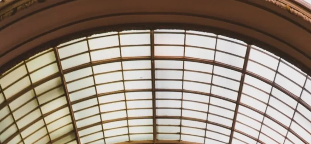 Curved glass ceiling with brown metal framework and translucent panels.