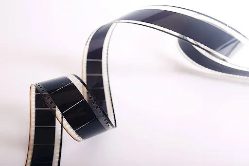 Black photographic film strip curled against a white background.